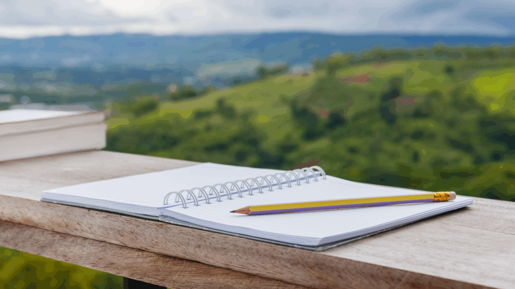 Calendar and pencil on balcony ledge overlooking view of forested hills