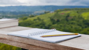 Calendar and pencil on balcony ledge overlooking view of forested hills