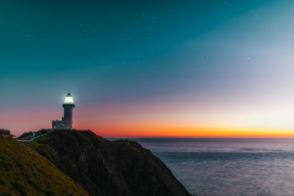 a light house by the coast beaming light into the sky