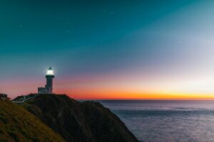a light house by the coast beaming light into the sky